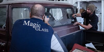 Technicians installing a back window in a vintage vehicle